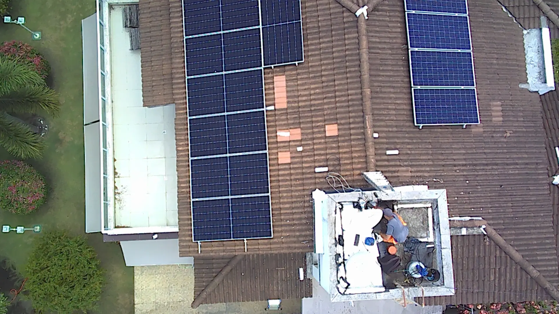 Vista aérea de equipe trabalhando na instalação de módulos fotovoltaicos em telhado residencial